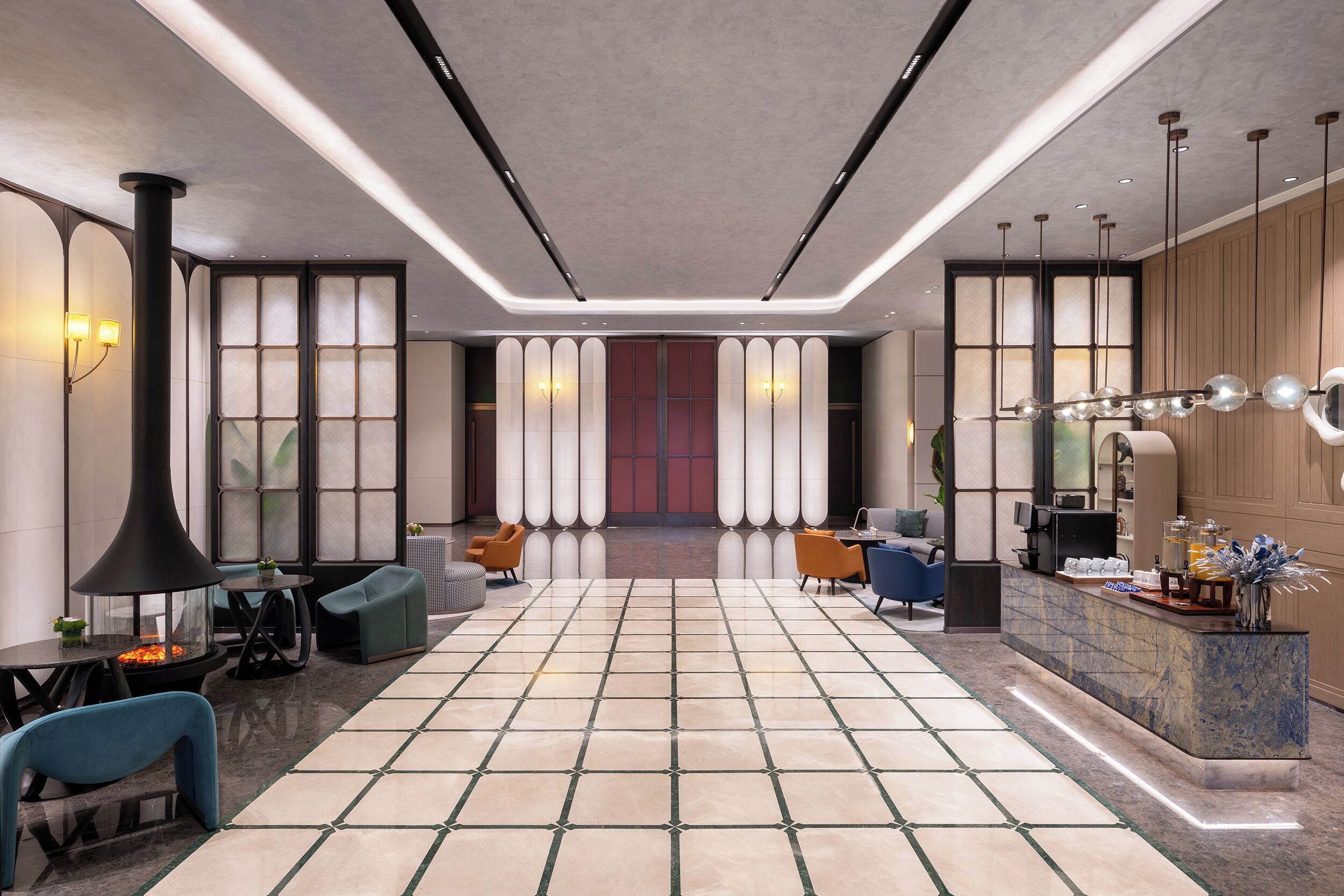 Um hall amplo com piso de azulejos, áreas de estar, balcão de recepção e uma grande janela com vista.