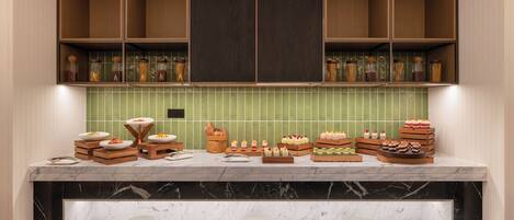 Une cuisine dotée de plans de travail en marbre, de meubles en bois et d’un dosseret de carreaux verts.