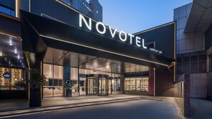 A hotel entrance with a revolving door, illuminated signage, and a modern facade. - Novotel Wuxi Sanyang Plaza (Wuxi)