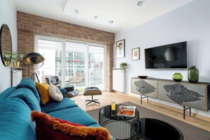 Ein Wohnzimmer mit Sofa, Couchtisch, Fernseher und Schrank.