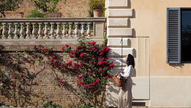 En person som står bredvid en byggnad med en tegelvägg och en balkong med ett räcke.