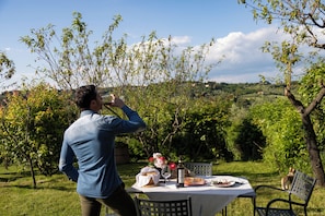 A person standing at a table with a bottle, a plate, and a glass. - Historic Tuscan Villa with frescoed halls (Toscana)
