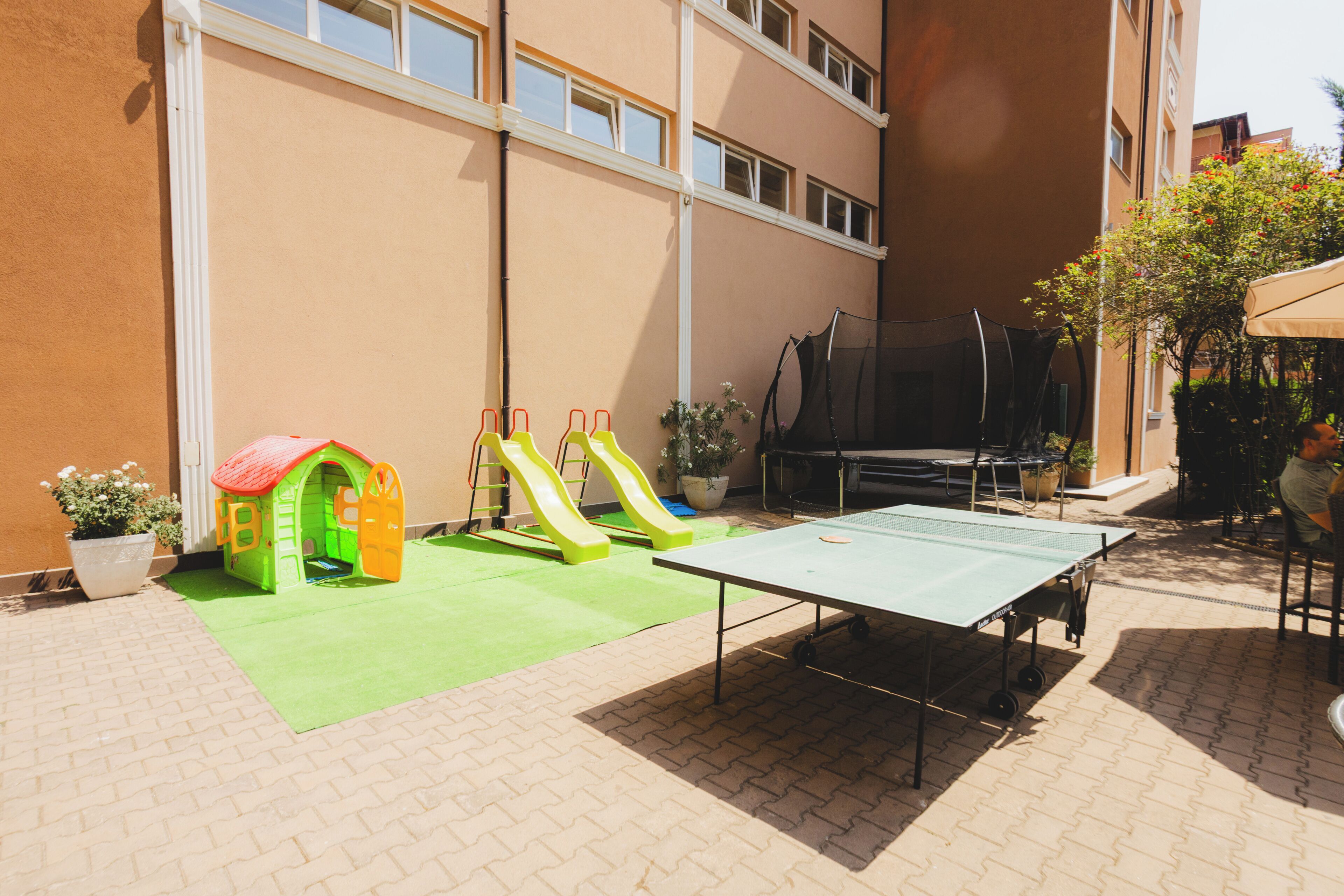 An outdoor play area with a slide, a small playhouse, and a ping pong table.