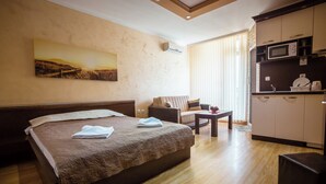 Een hotelkamer met een bed, een bank, een tafeltje, een magnetron en een schilderij aan de muur.
