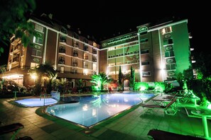 Un hôtel doté d’une piscine, d’un espace extérieur aménagé et d’une façade bien éclairée.