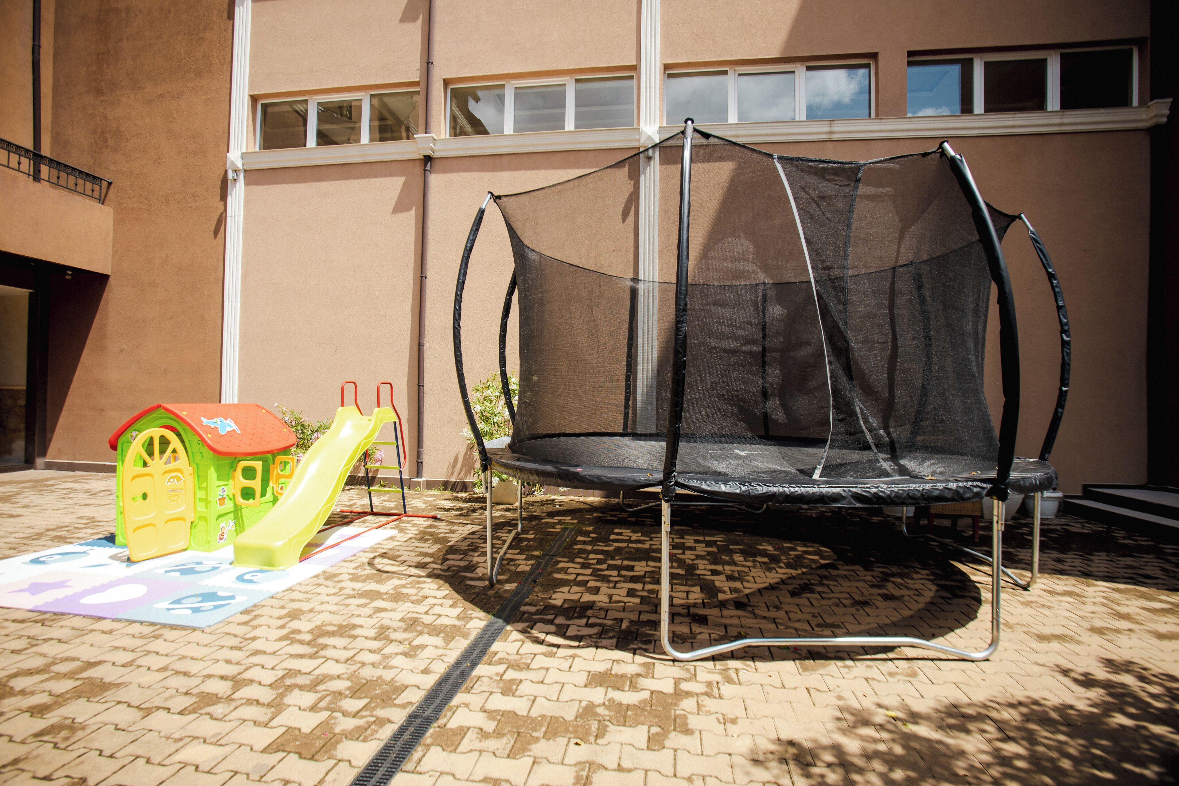 A trampoline with a safety net in front of a building with windows.