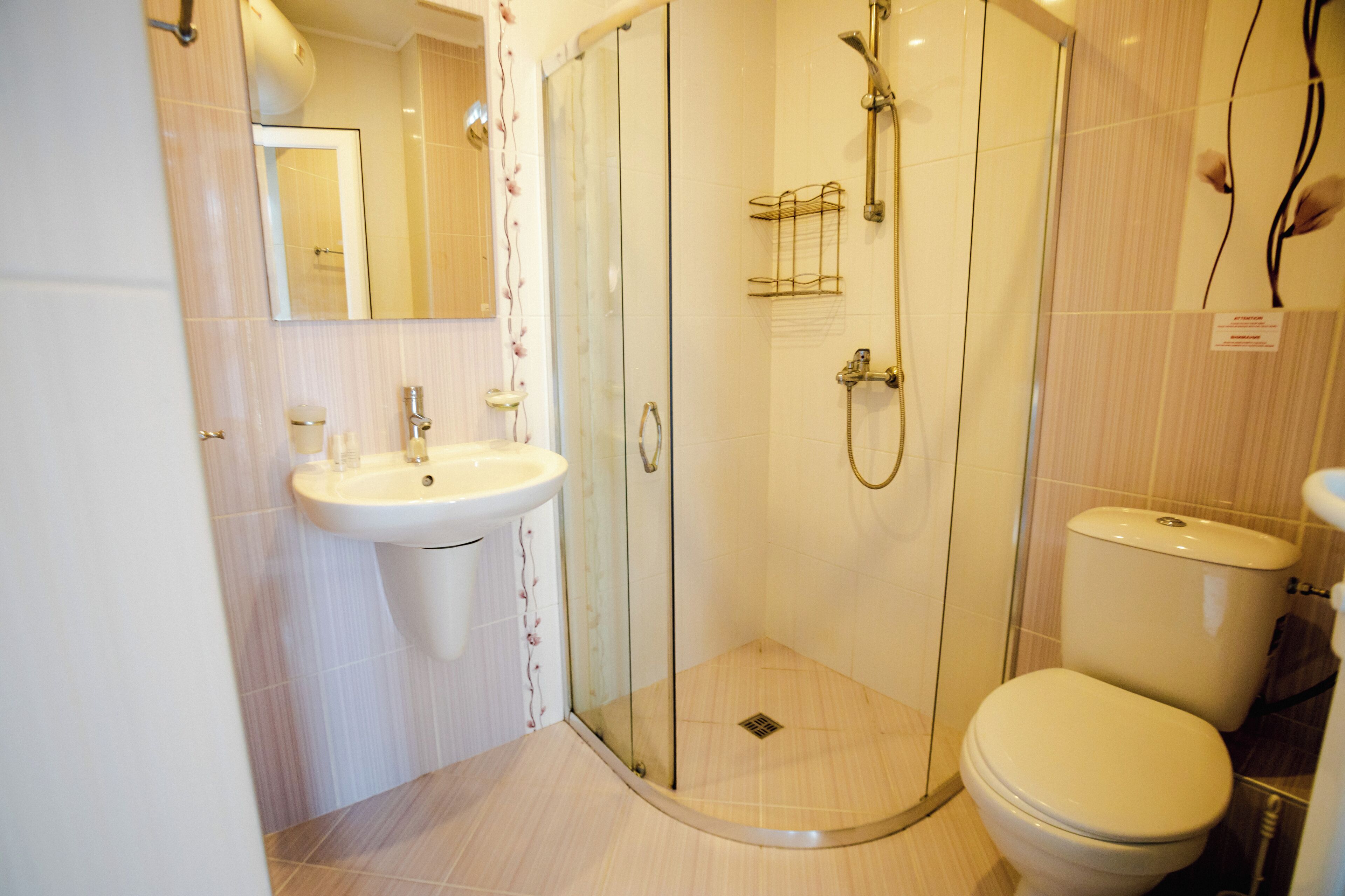 Un baño con ducha envuelta en vidrio, un lavamanos y un inodoro.
