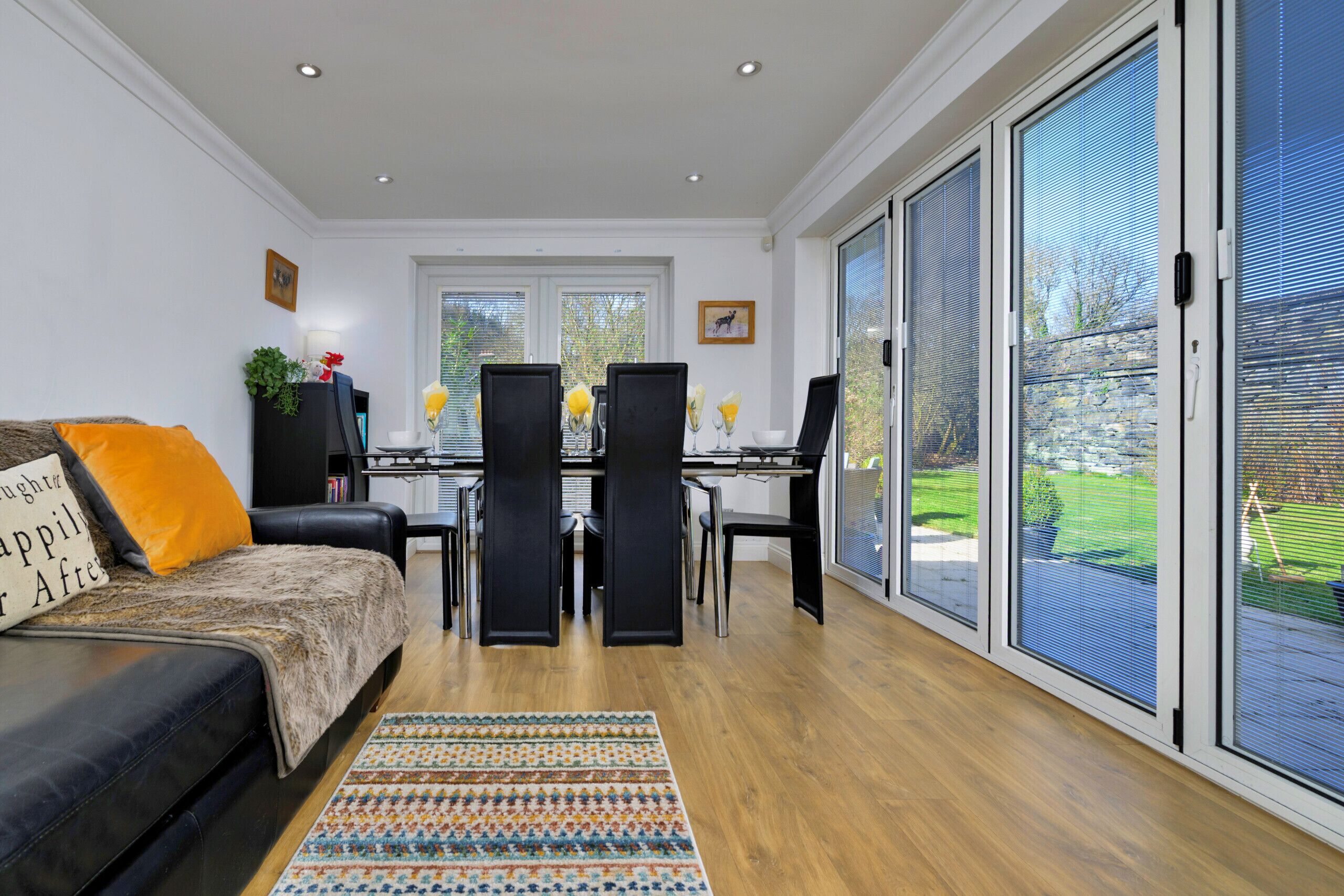 A living room with a sofa, a dining table with chairs, and large sliding glass doors to the outdoors.