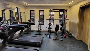 A gym with treadmills, a weightlifting station, and a mirror on the wall. - Goshen Trust Hotel And Suites (Idanre)