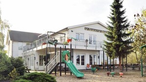 A building with a playground, including a slide and climbing structures, surrounded by greenery and a sandy area. - Hotel De Brabantse Biesbosch (Werkendam)
