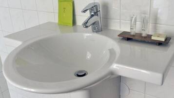 A bathroom with a white sink, chrome faucet, and a small shelf with toiletries.