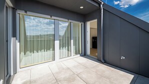 A modern building with a large sliding glass door leading to a balcony with a tiled floor. - A60 Boutique Hotel (Budapest)