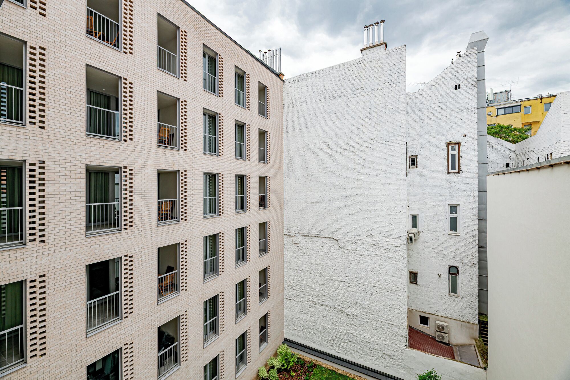 A multi-story building with a brick facade and white walls, featuring multiple windows and balconies.
