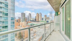 Un balcón con vista a la ciudad, que muestra modernos edificios altos y un cielo despejado.