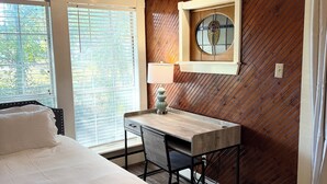 Un dormitorio con cama, escritorio y ventana.