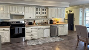 Una cocina moderna con armarios blancos, electrodomésticos de acero inoxidable y piso de madera.