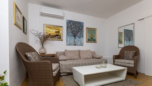 Een woonkamer met een bank, twee fauteuils, een salontafel en wanddecoratie.