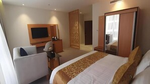 Une chambre d’hôtel équipée d’un lit, d’un bureau, d’une chaise, d’une télévision et d’une armoire.