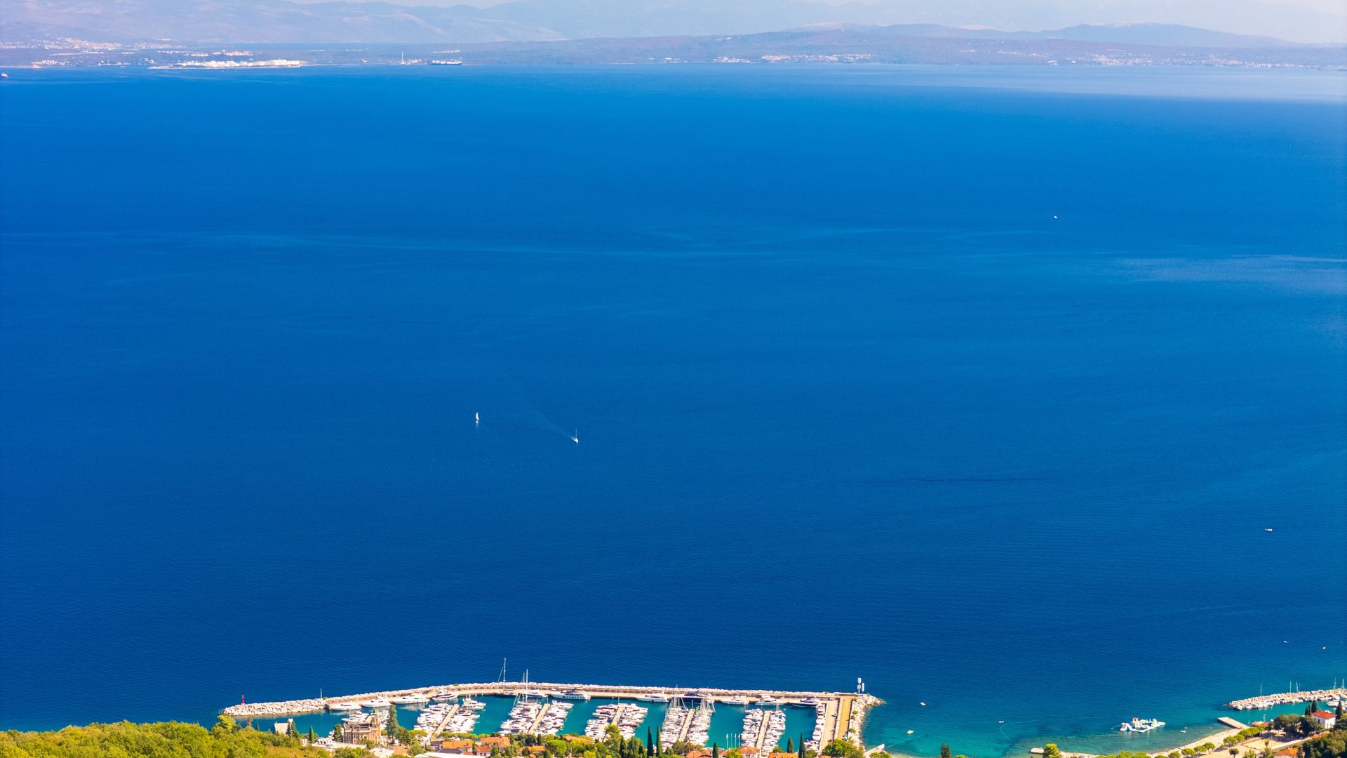 A coastal marina with boats docked and a pier extending into the water.