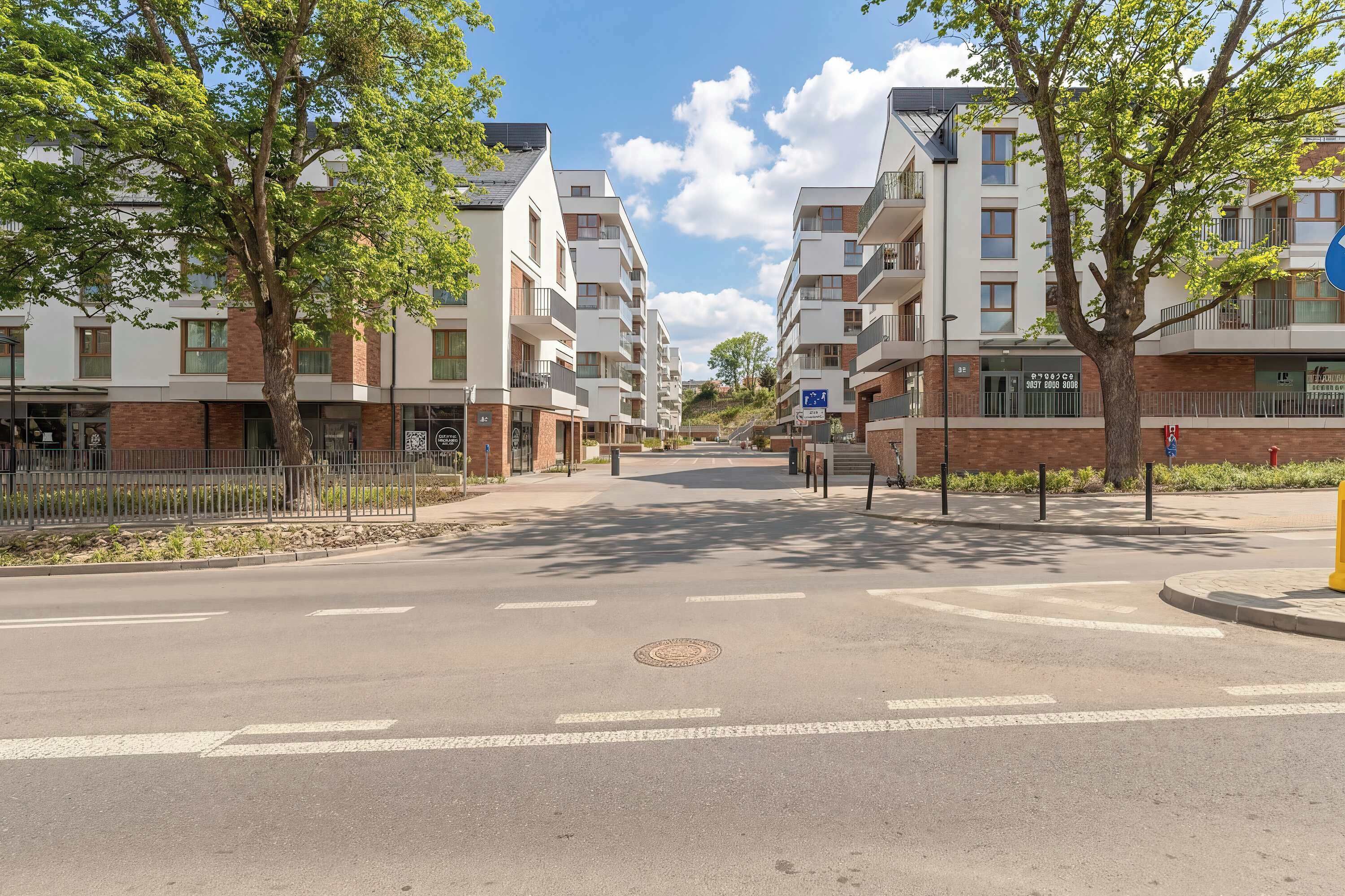 A multi-story residential building with balconies, a clear sky, and a pedestrian crossing.