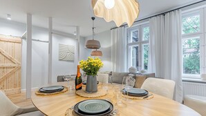 Un coin repas avec une table ronde dressée pour quatre personnes, une bouteille de champagne et un vase rempli de fleurs jaunes.