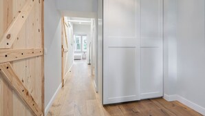 Un couloir aux murs lambrissés, une porte blanche et une vue sur une autre pièce.