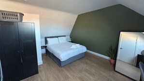 A bedroom with a bed, a wardrobe, a desk, a chair, and a potted plant. - Dublin citycenter 1 bedroom Apartment (Dublin)