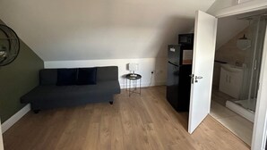 A compact living space with a sofa, a small table, a refrigerator, and a door leading to a bathroom. - Dublin citycenter 1 bedroom Apartment (Dublin)
