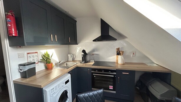 A compact kitchen with a washing machine, a coffee maker, and a fire extinguisher. - Dublin citycenter 1 bedroom Apartment (Dublin)