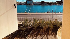 A view from a balcony overlooking a marina with boats, a building, and a clear blue sky. - JF IMMO-VILLA RARE GARDEN PRIVATE POOL 10 PEOPLE SEA VIEW V0861 (Agde)