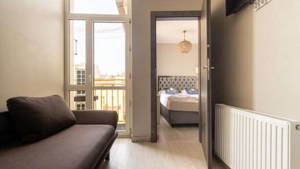 A room with a sofa, a bed with a headboard, a radiator, and a door leading to another room. - Imperial Apartments - GlobElite Sopot (Sopot)