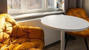 A room with a large window, a white table, and two yellow chairs. - Imperial Apartments - GlobElite Sopot (Sopot)