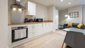 Una cocina moderna con gabinetes blancos, una campana extractora de acero inoxidable, un microondas y un horno empotrado.