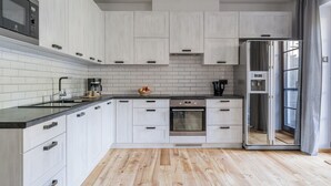 A modern kitchen with white cabinetry, a black countertop, and a built-in oven. - Imperial Apartments - Bernadowska (Gdynia)
