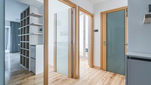 A modern interior with a wooden floor, a sliding glass door, a built-in shelving unit, and a refrigerator. - Imperial Apartments - Bernadowska (Gdynia)