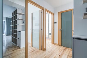 A modern interior with a wooden floor, a sliding glass door, a built-in shelving unit, and a refrigerator. - Imperial Apartments - Bernadowska (Gdynia)