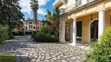 Un cortile con pavimento in pietra, un edificio con colonne e una palma.