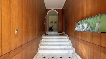 Una scala in marmo con pannelli di legno sulle pareti, che conduce a una stanza con una parete verde e una bacheca.
