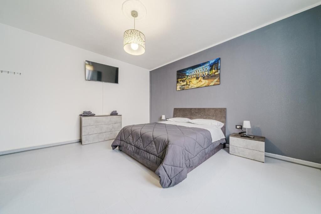 Ein modernes Schlafzimmer mit Bett, Nachttischen, Wandspiegel und Deckenleuchte.
