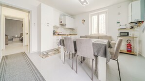 Moderni keittiö, jossa on valkoiset kaapit, ruokapöytä tuoleineen, mikroaaltouuni ja palosammutin.