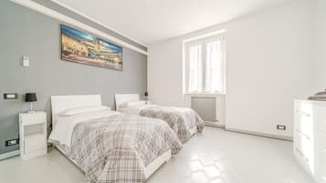 Een slaapkamer met twee bedden, een nachtkastje, een dressoir, een schilderij en een raam.