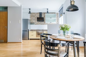 Eine moderne Küche mit Essbereich, ausgestattet mit einem Holztisch, Stühlen und einer Vase mit Blumen.