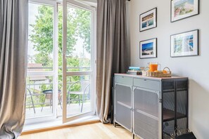 A room with a large window, a metal cabinet, and framed pictures on the wall. - Imperial Apartments - Nadmorski Zen (Sopot)