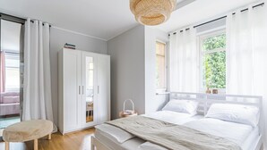 Une chambre à coucher avec un lit, une armoire, un banc et une fenêtre avec des rideaux.