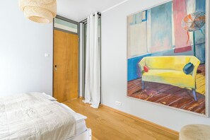 Ein Schlafzimmer mit Bett, einer Tür, einem Gemälde und einem Deckenventilator.