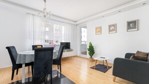 A modern living room with a dining area, a chandelier, a potted plant, and framed pictures on the wall. - RentPlanet - Apartament Skoroszewska (Warsaw)