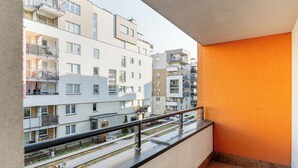 A balcony with a metal railing, a view of adjacent buildings, and a tiled floor. - RentPlanet - Apartament Skoroszewska (Warsaw)