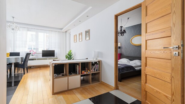 A modern bedroom with a wooden door, a bed, a desk, and a bookshelf. - RentPlanet - Apartament Skoroszewska (Warsaw)
