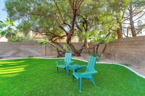 A backyard with a lawn, two chairs, and a tree.