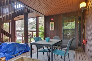 Un patio techado con una mesa y sillas, una terraza de madera y vistas al exterior.